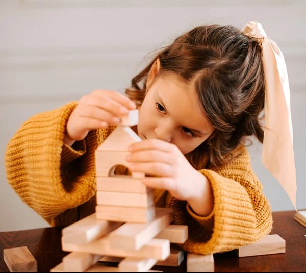 Child carefully playing with wooden building blocks